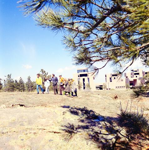 A group of people walk towards the foothills with the west side of the Mesa Lab behind them. The photo was taken during Earth Day tours of the Mesa Lab in 1970.