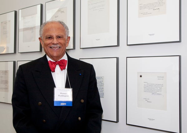 Warren in front of the American Academy of Arts and Sciences wall of acceptance letters.