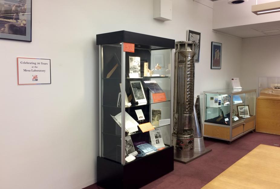 Picture of the exhibit featuring two exhibit cases and framed photos of the Mesa Laboratory