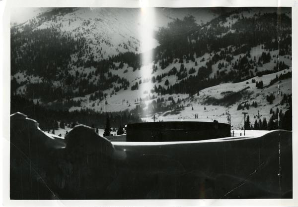 Vertical column of light with mountains in the background at night.