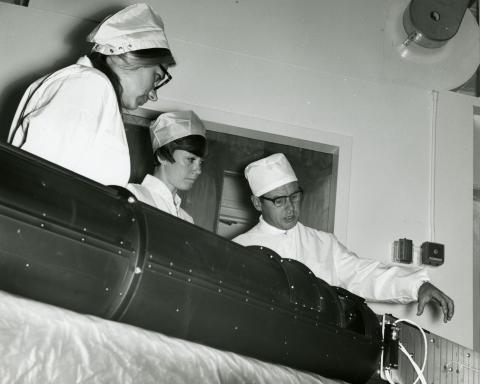 Kathy Strand, Kelly Dominguez, and Gordon Newkirk in a lab looking at an instrument.