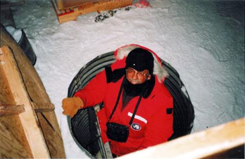 Warren on a ladder at the opening of a tunnel surrounded by snow.