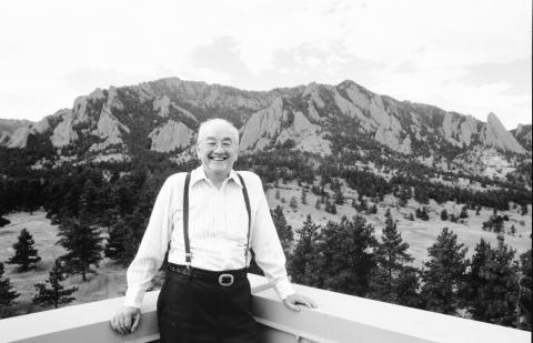Walter Orr Roberts Stands smiling on the roof of the Mesa Lab with the Flatirons in the background.