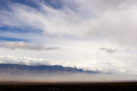 A dust storm forms in front of a mountain  range.