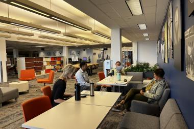 A group of people sit and talk in a meeting area of the library.
